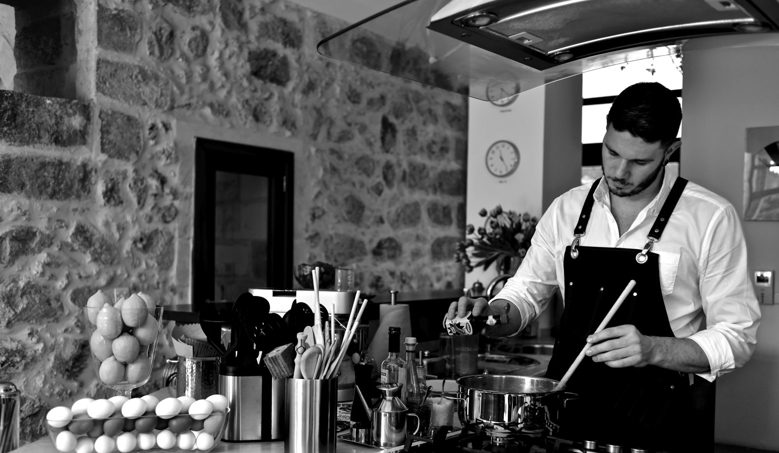 Sean Gravina cooking in a kitchen with a traditional Maltese stone wall
